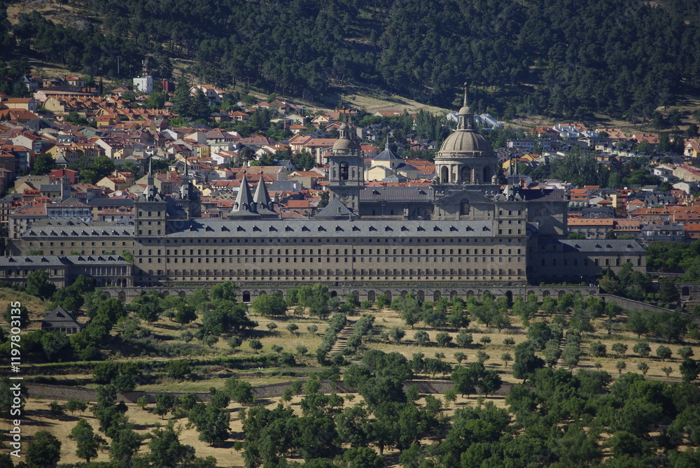 Fototapeta premium Vista del pueblo de San Lorenzo de El Escorial con diferentes arquitecturas y parte de naturaleza con su majestuoso edificio del Real Monasterio de San Lorenzo de El Escorial. Madrid. España
