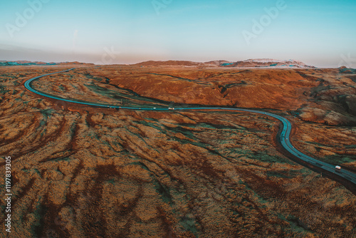 Aerial view of Iceland's Route 1 winding through Hellisheidi, surrounded by vibrant volcanic landscapes at sunrise. photo