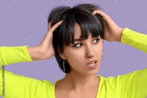 Stylish young woman with nose piercing on lilac background