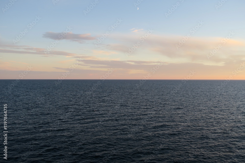 Die Sonne geht unter über dem Skagerrak an einem Sommerabend. Das Meer ist ruhig, und über dem Horizont sind ein paar Wolken zu sehen. Gesehen von Bord einer Fähre von Oslo nach Kopenhagen. Die Sonne geht unter über dem Skagerrak an einem Sommerabend. Das Meer ist ruhig, und über dem Horizont sind ein paar Wolken zu sehen. Gesehen von Bord einer Fähre von Oslo nach Kopenhagen.