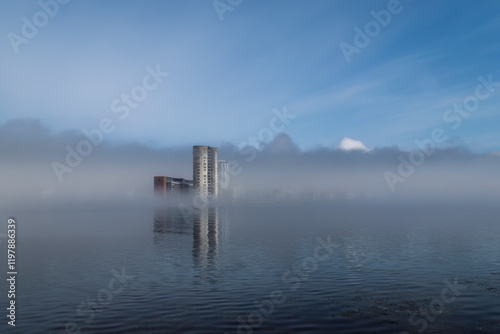 Aufnahme eines am Wasser stehenden hohen Gebäudes im Nebelmeer. photo