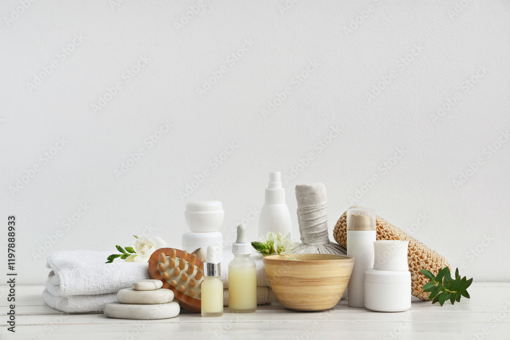 Composition with spa accessories, cosmetic products and flowers on light wooden table Composition with spa accessories, cosmetic products and flowers on light wooden table