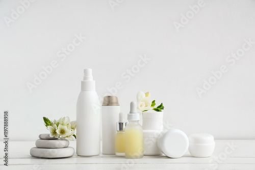 Set of different cosmetic products, spa stones and beautiful flowers on light wooden table