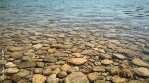 Clear water reveals smooth, multicolored stones under a calm lake surface.