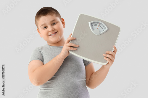 Overweight young boy holding weight scale, childhood obesity and health awareness, weight management and healthy lifestyle