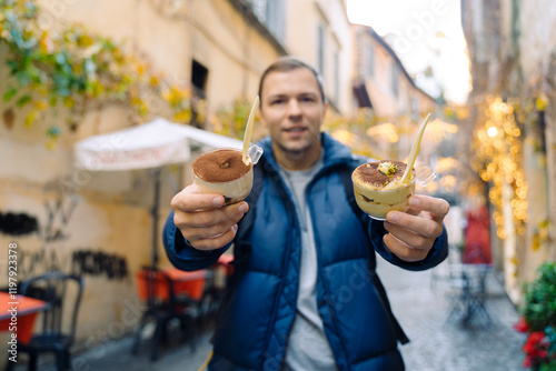 A man holds in her hand a traditional Italian dessert tiramisu against the background of a street in Rome in Italy. photo