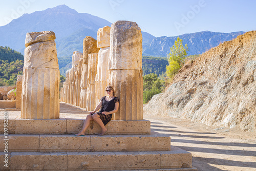 girl sitting at the base of antique columns
