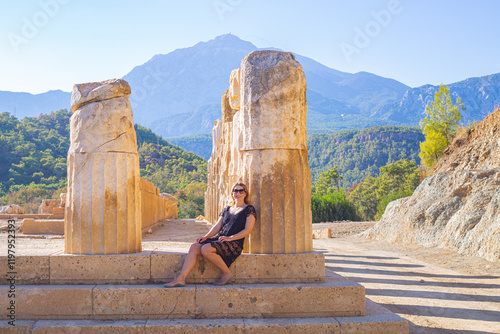 girl sitting at the base of antique columns
