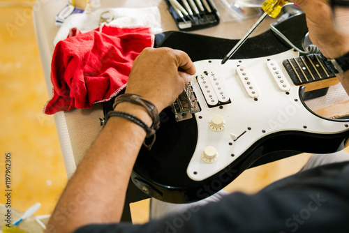 Luthier carefully repairing electric guitar in workshop