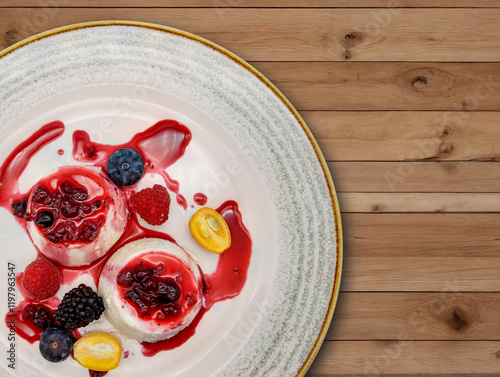 Panna Cotta mit Beeren und Fruchtsauce auf elegantem Teller, präsentiert auf rustikalem Holzhintergrund