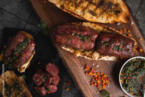 A choripan with chimichurri sauce on a wooden board. Traditional argentinian sandwich.  photo