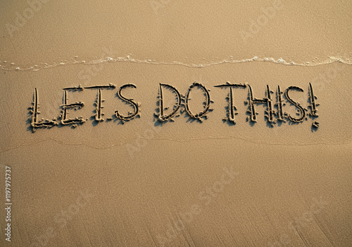 Sand writing on beach with motivational message Lets Do This in golden sand under gentle wave photo