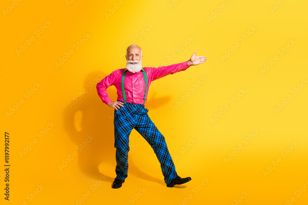 Full body photo of bearded gentleman dance point empty space wear fashionable clothes suspenders isolated on vibrant yellow background Full body photo of bearded gentleman dance point empty space wear fashionable clothes suspenders isolated on vibrant yellow background