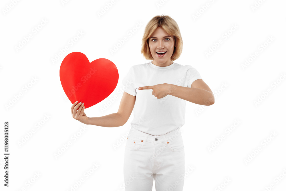 Happy young blonde woman in casual white outfit point finger on paper heart over white background. Valentines Day. Happy young blonde woman in casual white outfit point finger on paper heart over white background. Valentines Day.