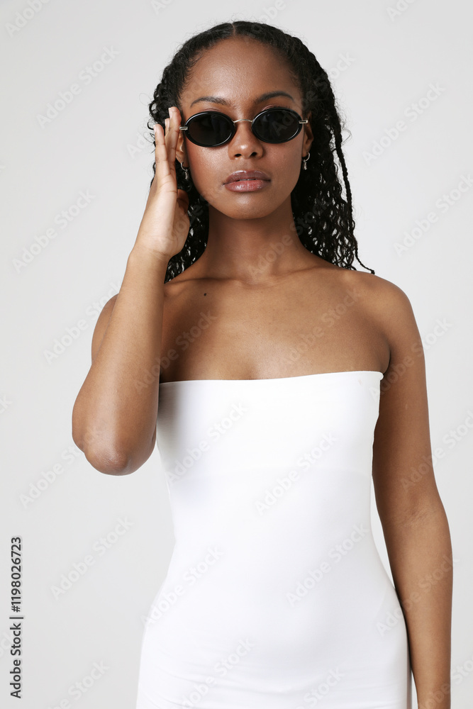 Portrait of lovely female with dark skin wears sunglasses posing over white background. Vertical close-up. Portrait of lovely female with dark skin wears sunglasses posing over white background. Vertical close-up.