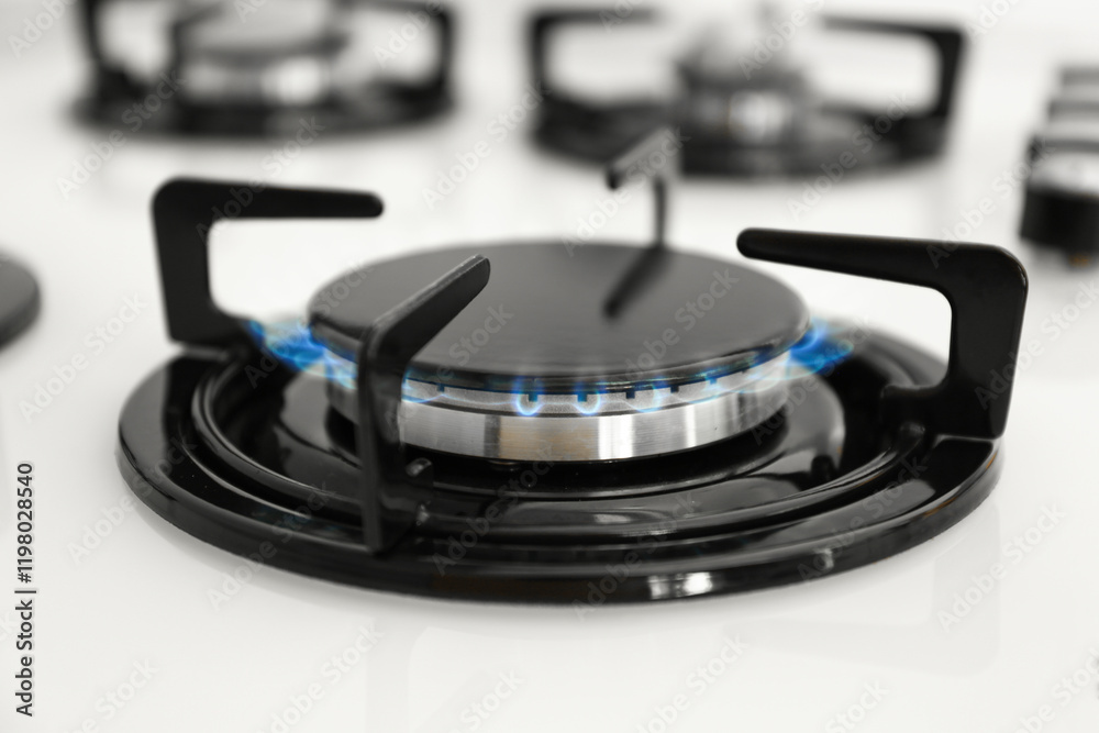 Gas burner of modern stove with burning blue flame, closeup Gas burner of modern stove with burning blue flame, closeup
