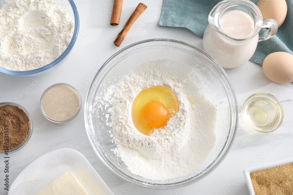 Making cinnamon rolls. Different ingredients for dough on white marble table, flat lay Making cinnamon rolls. Different ingredients for dough on white marble table, flat lay