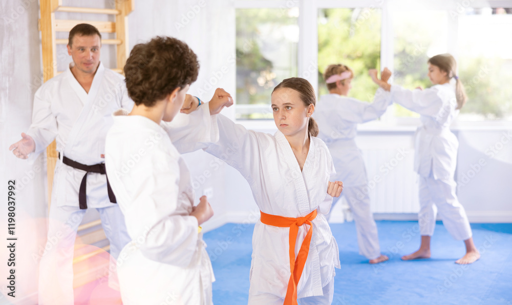 Child boys and girls partners during martial arts karate class train to perform basic blows to opponent with hands and feet. Preparation of athletes for competitions Child boys and girls partners during martial arts karate class train to perform basic blows to opponent with hands and feet. Preparation of athletes for competitions