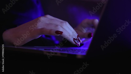 Young woman working on laptop. Purple lighting, night