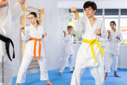 Kata karate teacher conducts classes and performs movements and fighting techniques together with boys and girls students to prepare them for competitions. photo