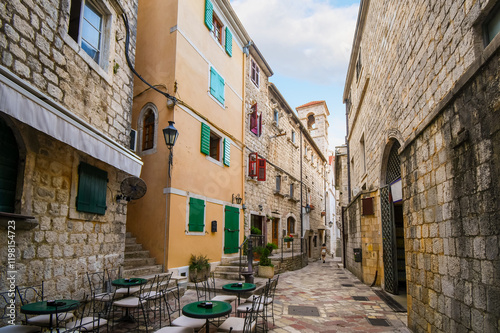 A narrow alley of shops and sidewalk cafes in the historic medieval old town of Kotor, Montenegro.