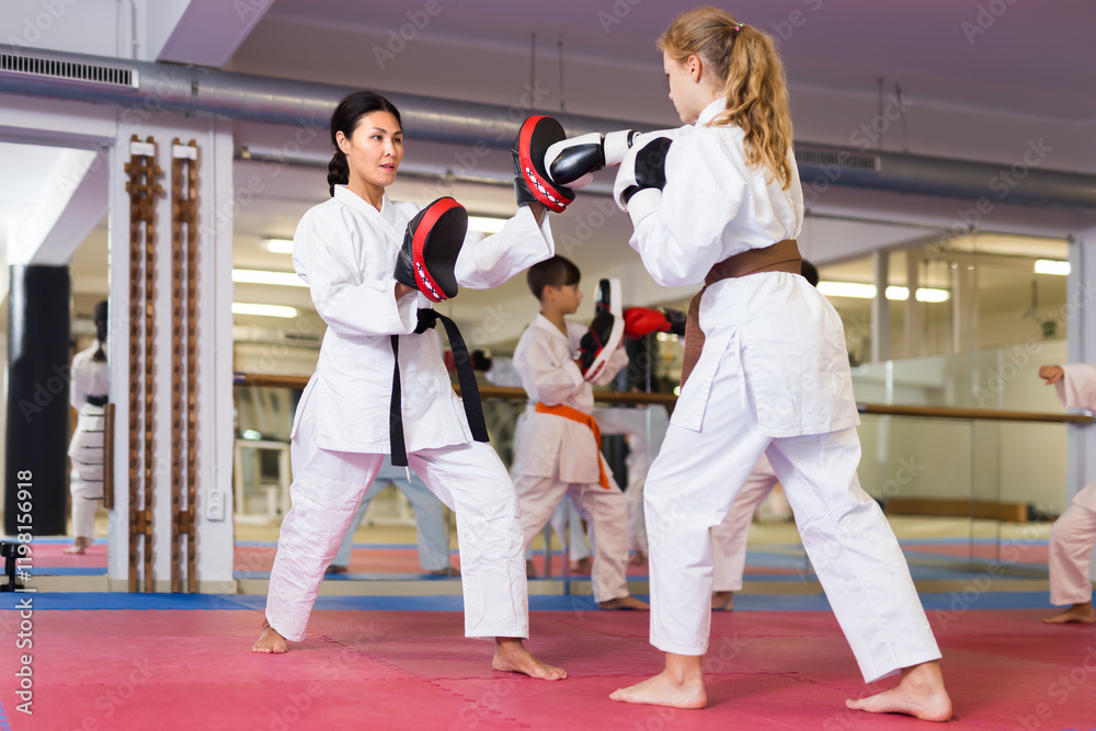 Female trainer in boxing gloves conducts sparring and teaches punches to a girl in karate and self-defense training Female trainer in boxing gloves conducts sparring and teaches punches to a girl in karate and self-defense training