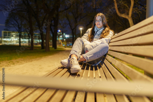 Young woman sitting on the bench at night..