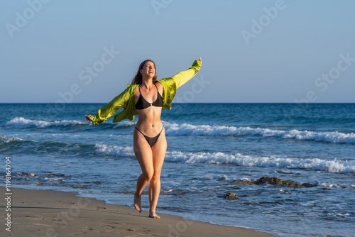 Young white woman in black bikini on the beach at sunset