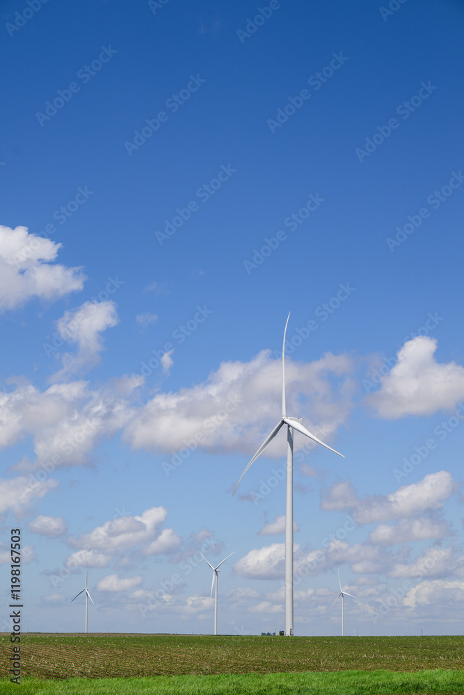 Giant white wind turbine windmill with blue sky and cumulus clouds Giant white wind turbine windmill with blue sky and cumulus clouds