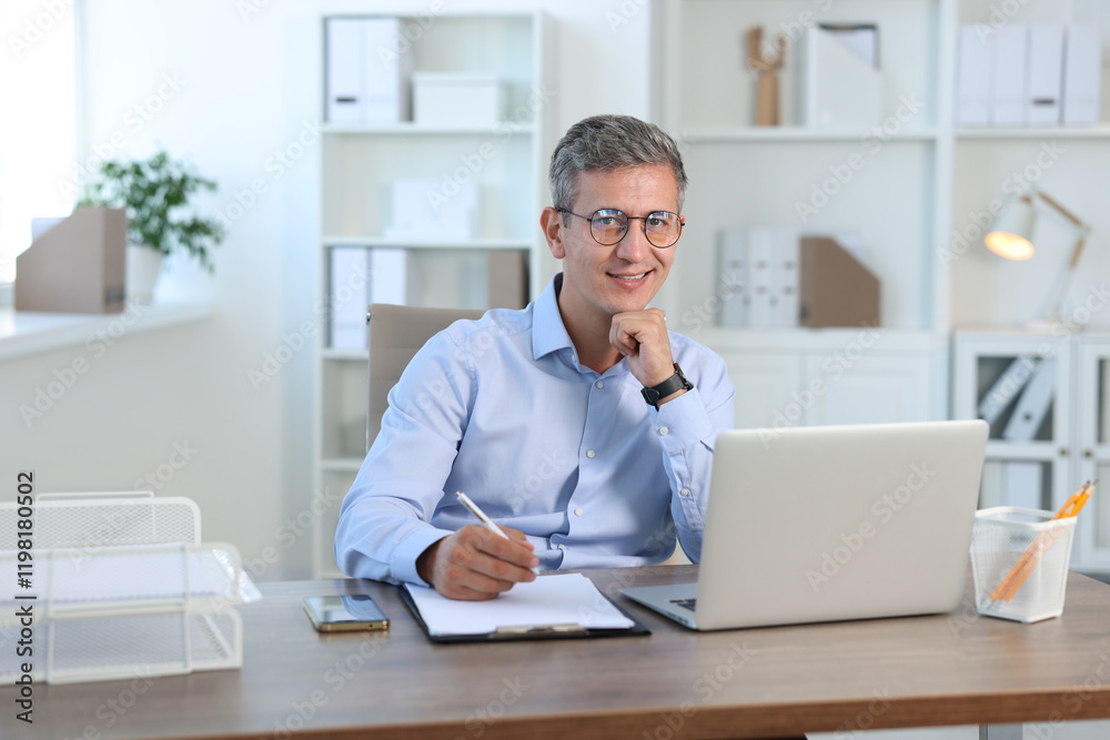 Portrait of smiling middle aged man at table in office Portrait of smiling middle aged man at table in office