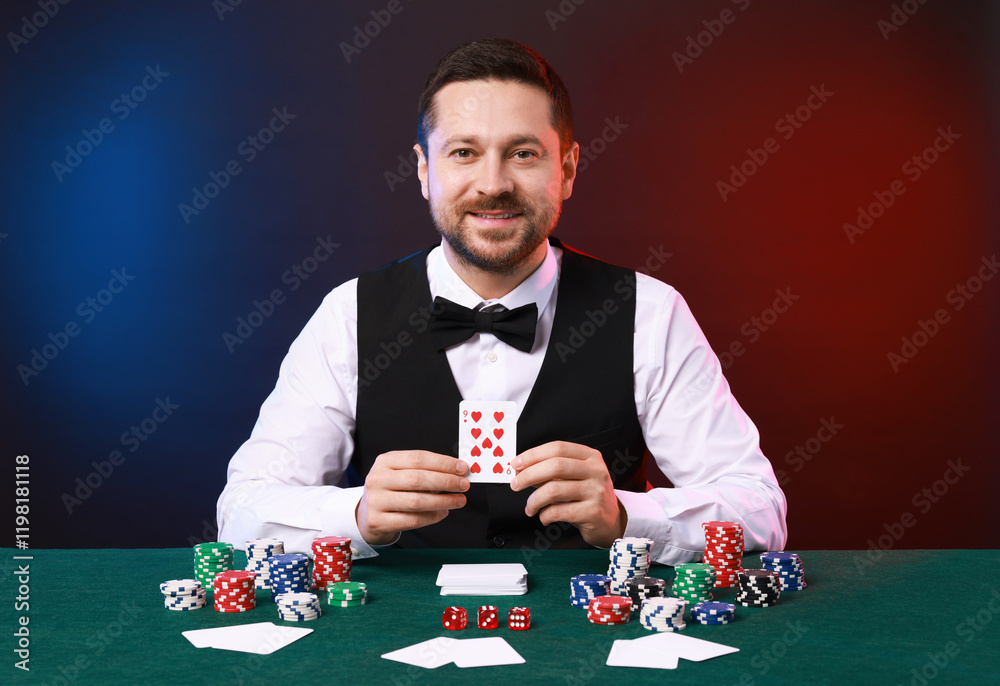 Professional croupier with playing card at gambling table against color background Professional croupier with playing card at gambling table against color background