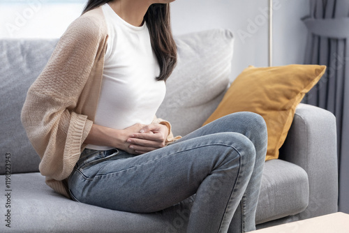 Attractive Asian young woman suffering from stomach ache, gastritis, menstruation, colitis, concept of female stomach ache.