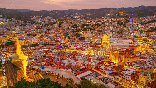 Aerial photo of the city of Guanajuato during the early evening hours. The lights of its emblematic colonial sites stand out. The Basilica and the University look beautiful.