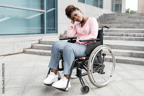 Inaccessible city environment for people with special needs. Upset young black lady suffering from lack of wheelchair friendly facilities, cannot enter building without ramp, blank space photo