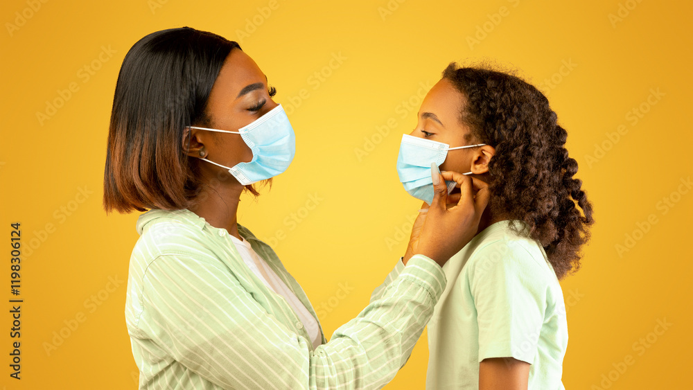 © Prostock-studio - Loving african american woman putting medical mask on his cute daughter face, yellow background. Mother and girl going out during COVID-19 pandemic, parent helping child to wear protective face mask © Prostock-studio - Loving african american woman putting medical mask on his cute daughter face, yellow background. Mother and girl going out during COVID-19 pandemic, parent helping child to wear protective face mask