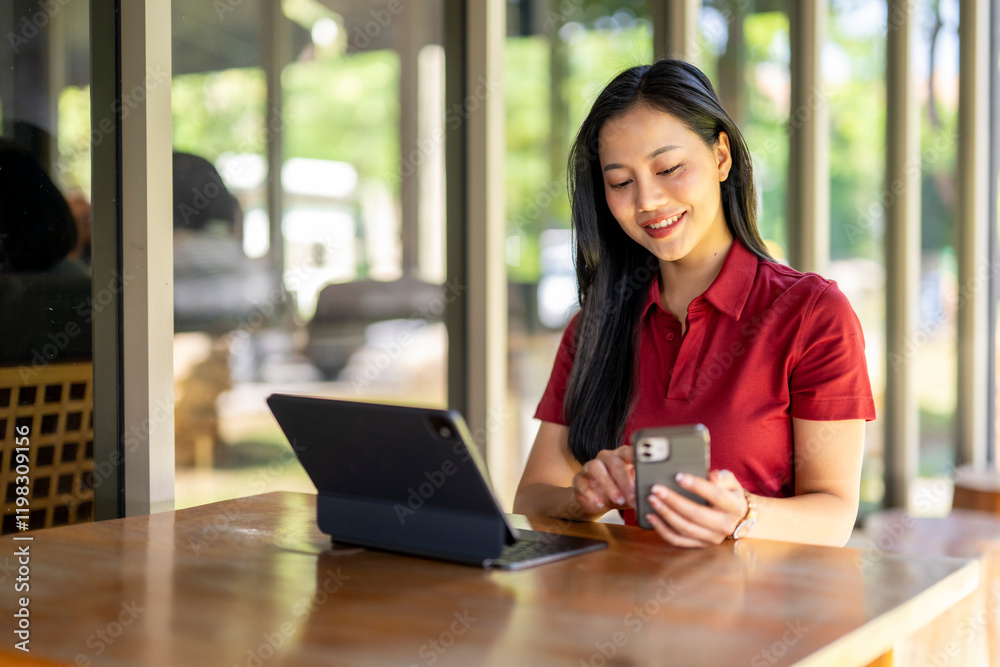 A woman is sitting at a table with a laptop and a cell phone A woman is sitting at a table with a laptop and a cell phone