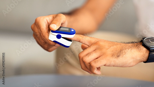 Unrecognizable man using modern pulse oximeter, closeup photo, copy space. Cropped of male patient putting clip-like small device for blood oxygen, saturation measuring and coronavirus