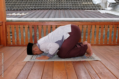 Muslim person praying indoors in traditional attire