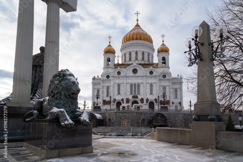 Cathedral of Christ the Savior on the background of a bronze sculpture of a lion at the foot of the monument to Alexander II the Liberator on a sunny winter day, Moscow, Russia