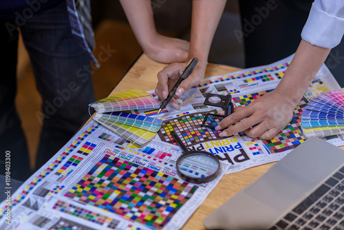 Team graphic designer checking print quality of media graphics proof print and color guides in printing industry. Selected focus