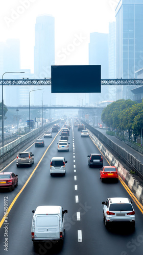 A busy urban highway with various vehicles traveling, surrounded by buildings and a foggy skyline, featuring a large blank advertising screen overhead.