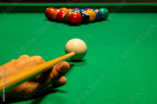 Jogador de sinuca iniciando o jogo com a bola branca alinhada ao triângulo de bolas coloridas na mesa verde photo