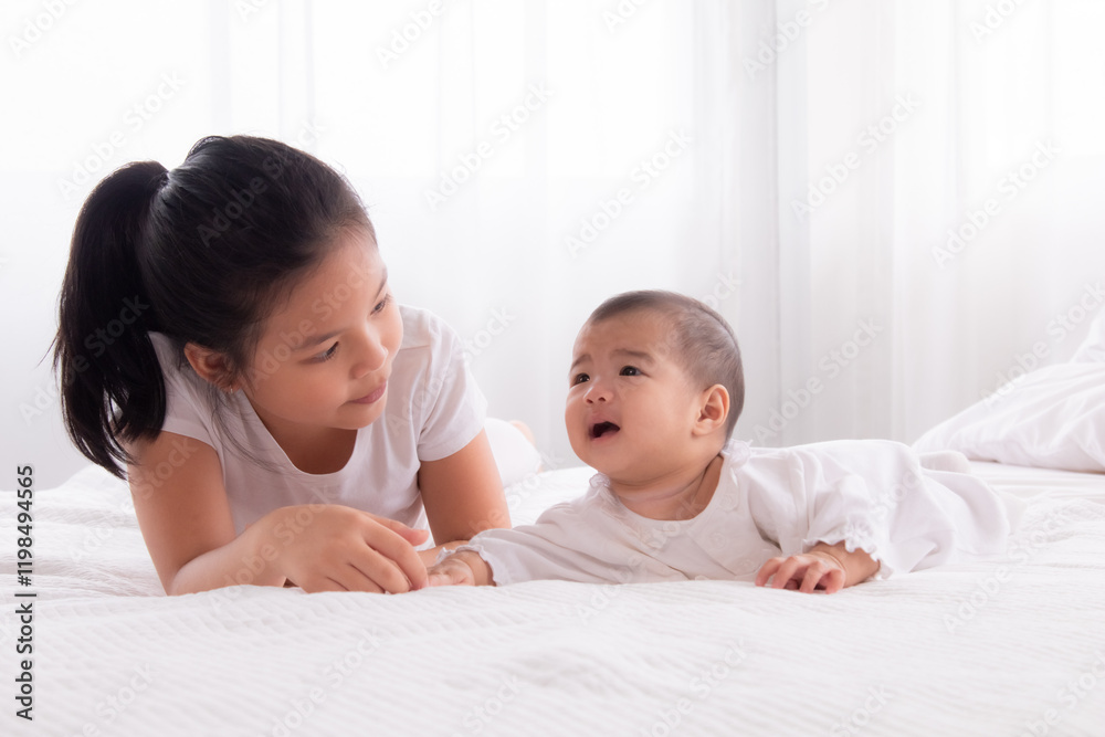Asian siblings love bonding relationship, adorable younger sister playing with toddler baby on bed soft touching, happy kid nursing hugging embracing together, preschool girl spend the holiday at home Asian siblings love bonding relationship, adorable younger sister playing with toddler baby on bed soft touching, happy kid nursing hugging embracing together, preschool girl spend the holiday at home