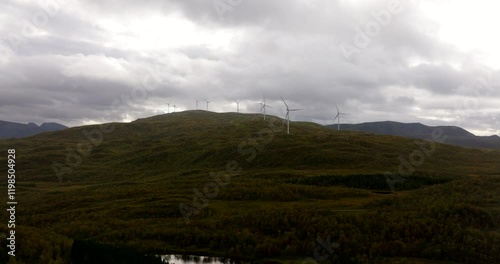 Rotating Wind Turbines Over Mountains Against Cloudy Sky In Sortland, Norway. Aerial Drone Shot photo