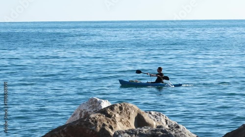 Zoagli, Genoa, Italy - November 15, 2024. Man sailing a canoe on sea. Sport and health.  photo