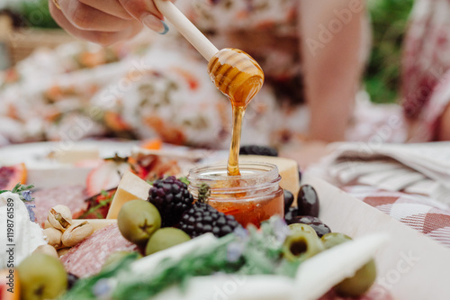 Honey drizzling onto a charcuterie board outdoors.