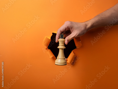 A hand emerges from a torn orange background, holding a light-colored chess queen.  It symbolizes strategic thinking, breakthrough, and decisive action.