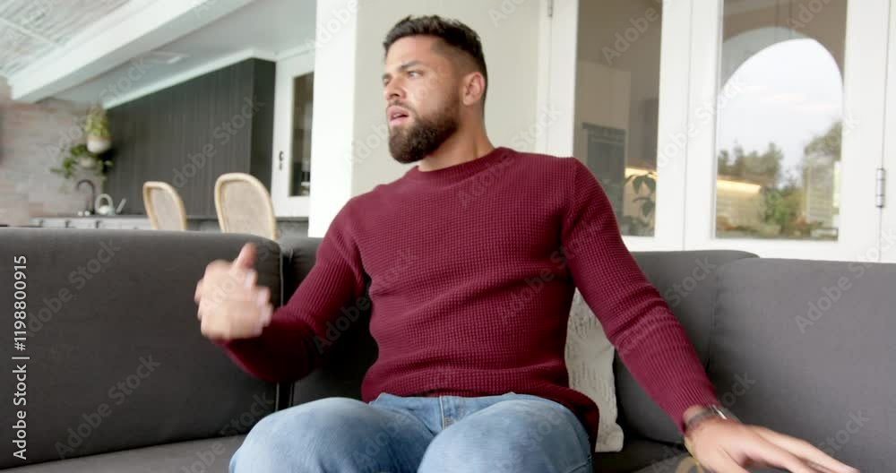 Sitting on couch, man annoyed looking at message on phone in modern living room
