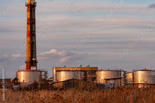 Industrial Facility With Silos and Smoke Stack During Sunset