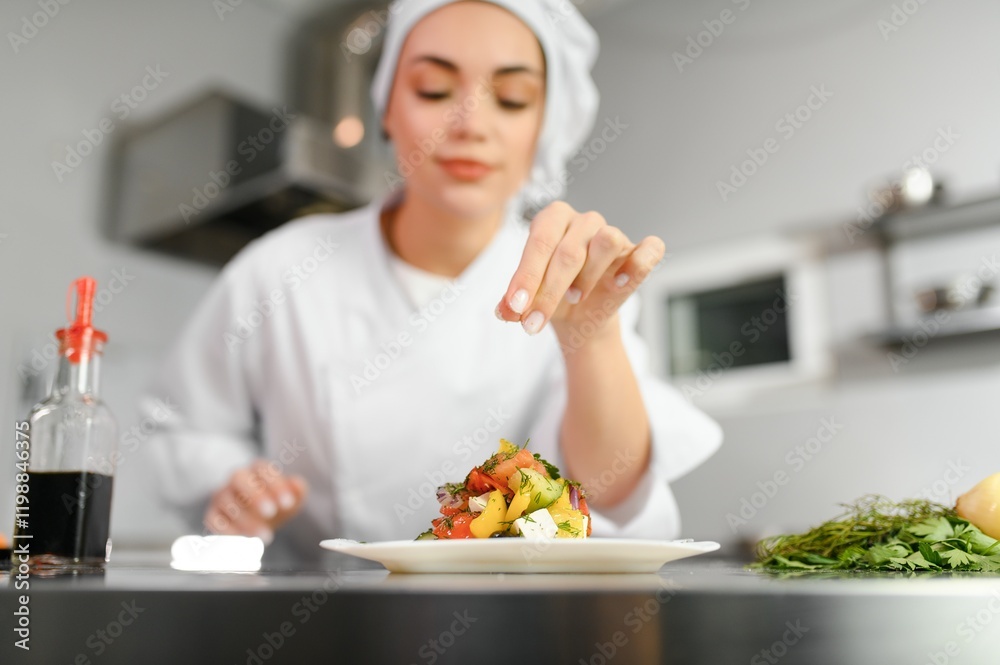 young beautiful smiling woman chef wearing in white suit at kitchen. Blurred background young beautiful smiling woman chef wearing in white suit at kitchen. Blurred background